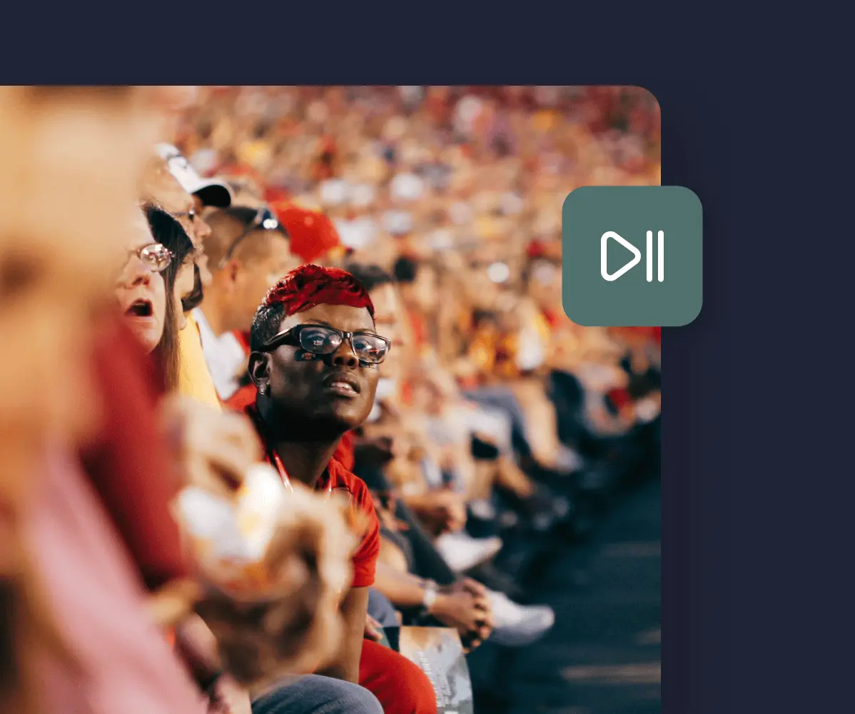 fans watching a game with a play/pause icon top right